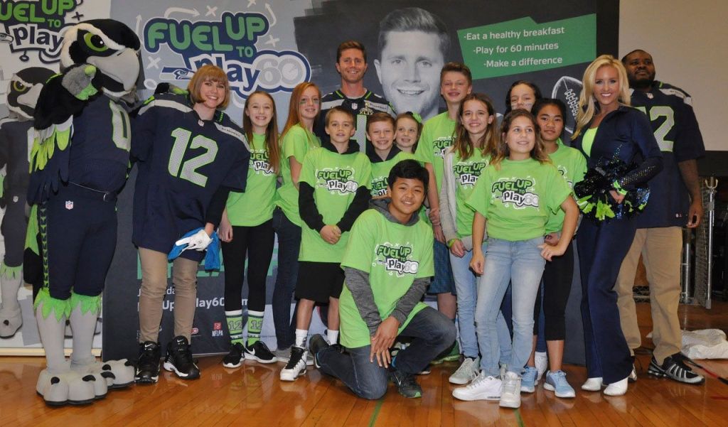 From left: Blitz, teacher Joette Dunnihoo, Seahawk Steven Hauschka, SeaGal Melody, and teacher Joshua Easley with students in Play 60 shirts. RACHEL CIAMPI, Auburn Reporter