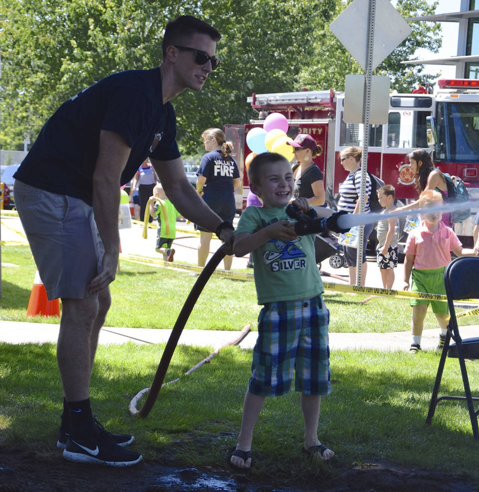 Fireman Erik Peterson has Wyatt Willits, 6, spray the hose. RACHEL CIAMPI, Auburn Reporter