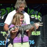 Don &ldquo;The Reptile King&rdquo; Riggs has Angelina Puskar, 8, hold his alligator, Lator, during festivities at Algona Days at Matchett Park last Saturday. RACHEL CIAMPI, Auburn Reporter