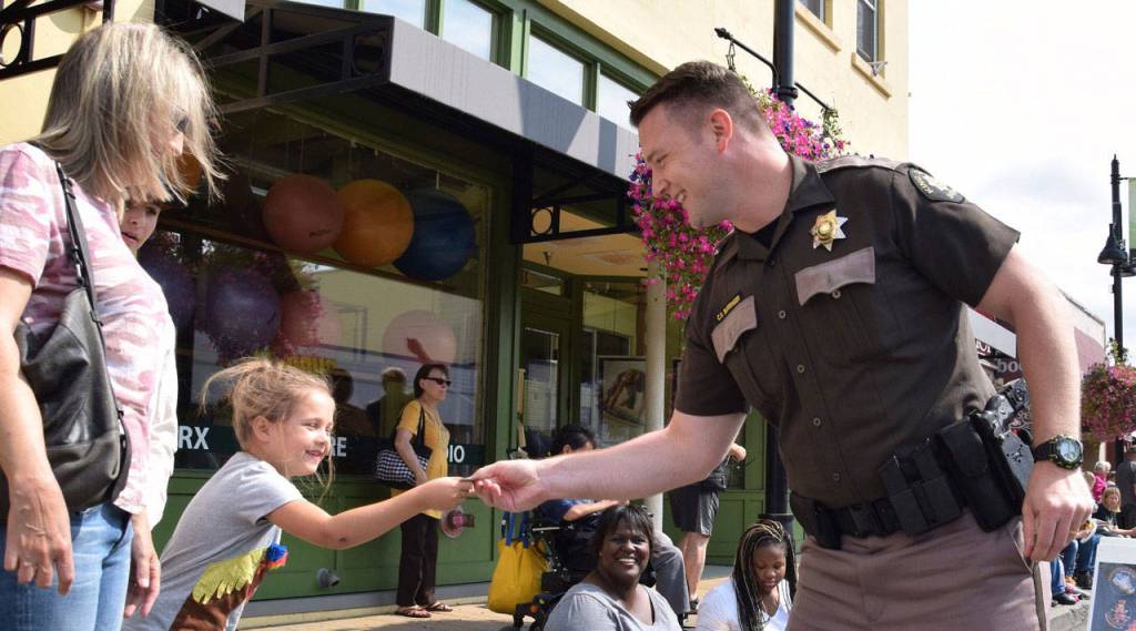 Deputy C.R. Barringer gives Halen Harkey a sticker in the parade. RACHEL CIAMPI, Auburn Reporter