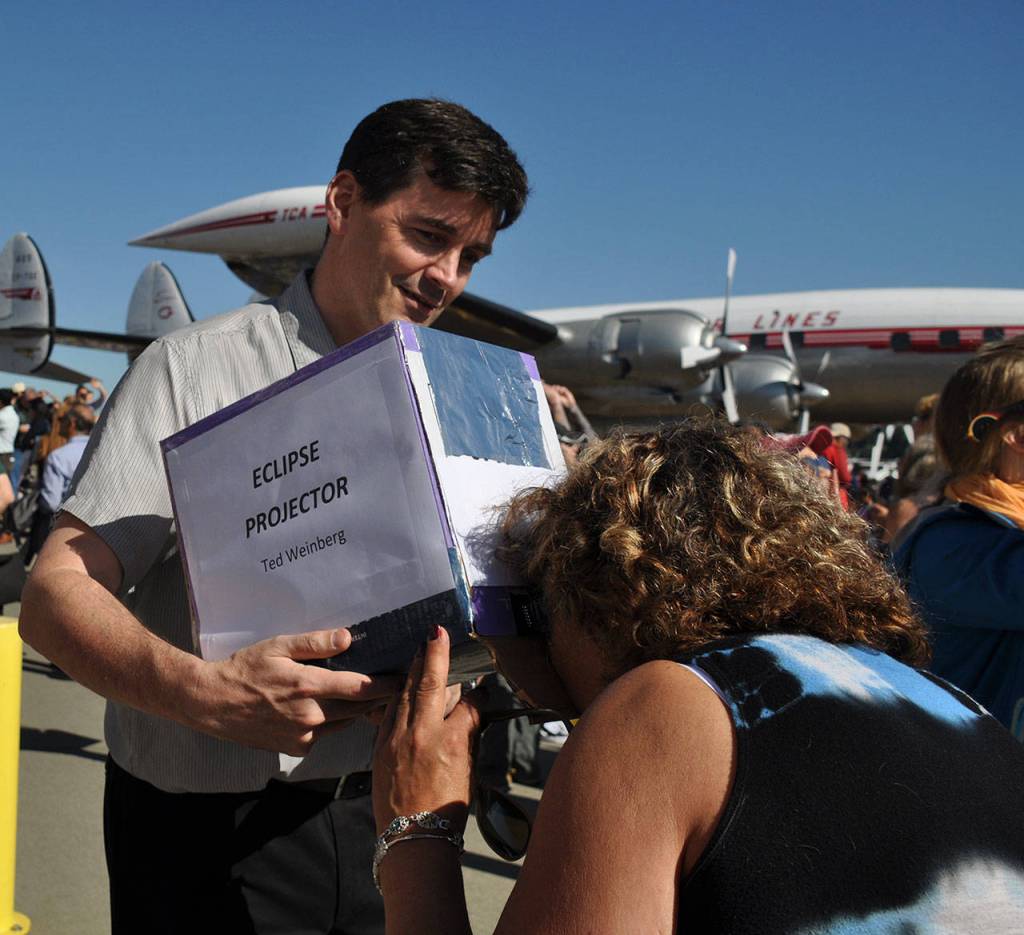 Ted Weinberg, left, helps a woman view the eclipse through a projector he made. HEIDI SANDERS, Reporter