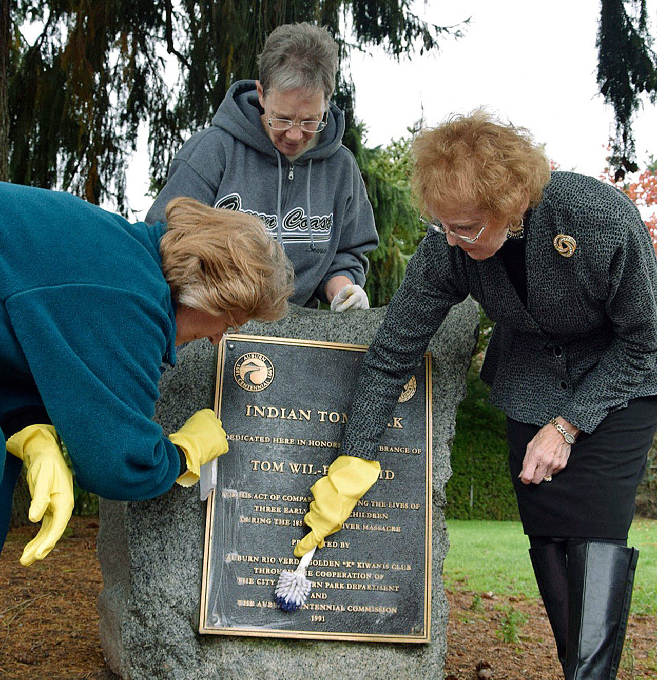 Volunteers, from left, Fran Hollums, Linda Hansen and Hilda Meryhew clean the Indian Tom Park centennial marker at Indian Tom Park on Sunday. The marker was dedicated in honored remembrance of Tom Wil-Etch-Tid for his act of compassion in saving the lives of three early pioneer children during the 1855 White River Massacre. The Auburn Rio Verde Golden &ldquo;K&rdquo; Kiwanis Club – through cooperation of Auburn Parks, Arts and Recreation Department and the Auburn Centennial Commission of 1991 – presented the marker. RACHEL CIAMPI, Auburn Reporter
