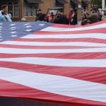 A large flag is unfurled during the parade march. RACHEL CIAMPI, Auburn Reporter