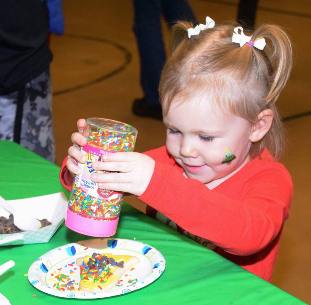 Kinley Millen, 2, adds some sprinkles to her Christmas cookie during the Holiday Snack Craft activity at Washington Elementary. RACHEL CIAMPI, Auburn Reporter