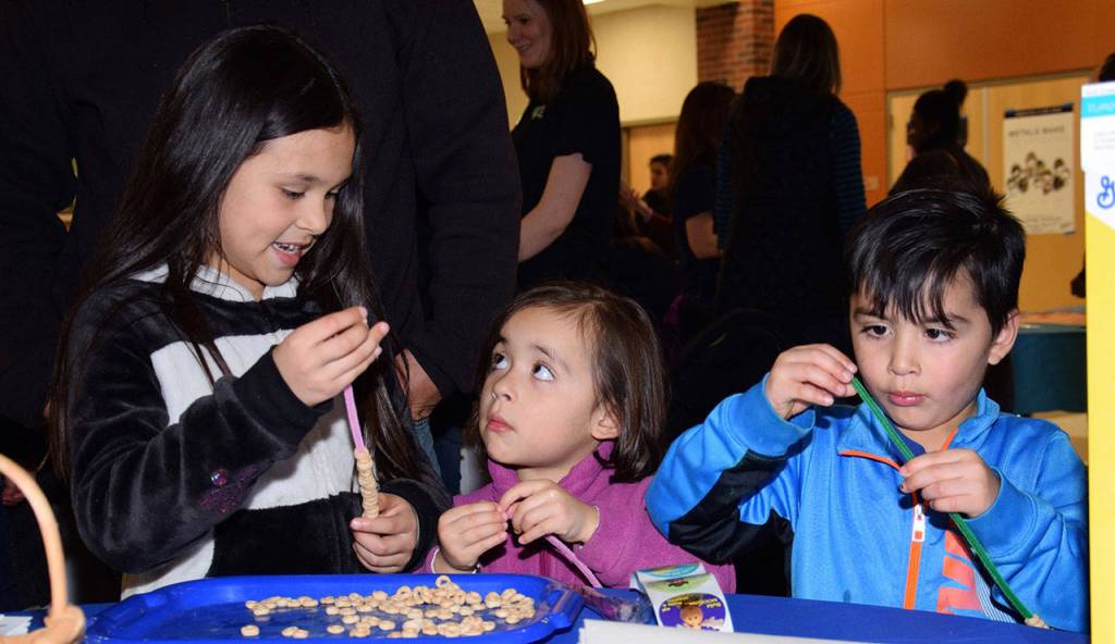 Leah, 9, Jazlyn, 4, and Icker Gaytan, 4, make bird feeders at the Early Learning Fair. RACHEL CIAMPI, Auburn Reporter