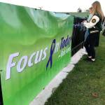 Auburn High Schools Jayden Henry (lettermans jacket), students and staff begin to tie ribbons to a fence along Bob Jones Way early Monday morning. The attached poster, Focus On Today, is a familiar Jones saying and honors the late coach, teacher and mentor on the one-year anniversary of his death to cancer. MARK KLAAS, Auburn Reporter
