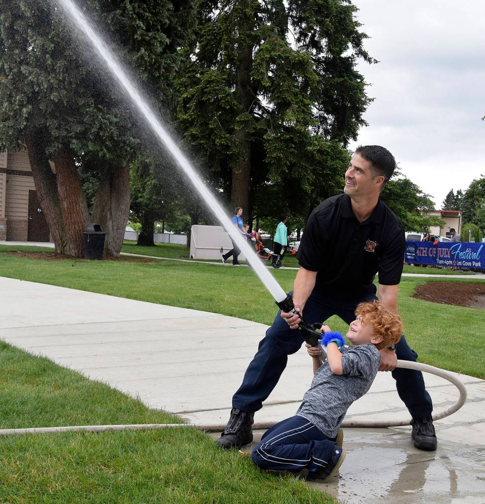 Valley Regional Fire Authority firefighter Cory Wallace has Hunter Stover, 7, fire water from the hose. RACHEL CIAMPI, Auburn Reporter