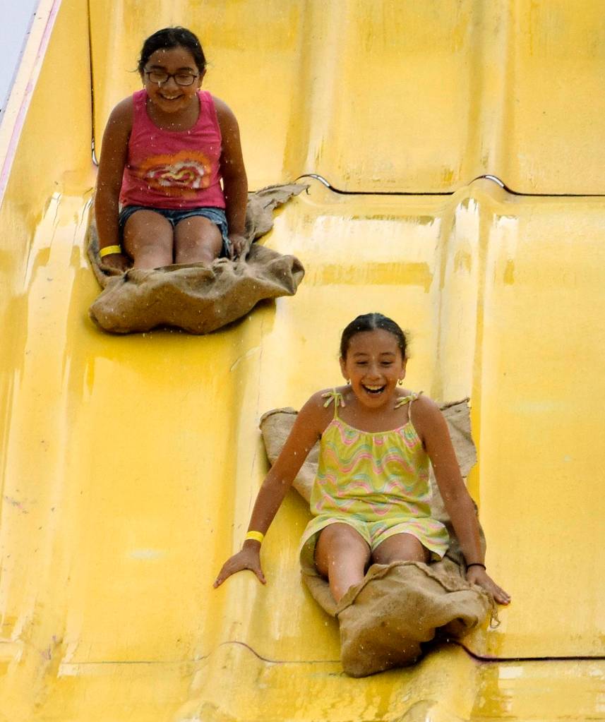 Joycelyn, 10, and Lupe Gutierrez, 7, sail down the slide in the rain at AuburnFest in the park. RACHEL CIAMPI, Auburn Reporter