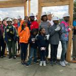 The Kayembe family joins Delta Airlines volunteers who erected a frame on the foundation of their new home in Pacific during a Habitat for Humanity Seattle-King County kickoff ceremony Sept. 11. COURTESY PHOTO