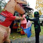 Left, Sebastian Bane, 5, gets a toothbrush from T-Rex. Right, Krystal Sanders as a pirate has Shaylee Bonzan, 9, and Landon Gregory, 7, pluck candy from the treasure chest.