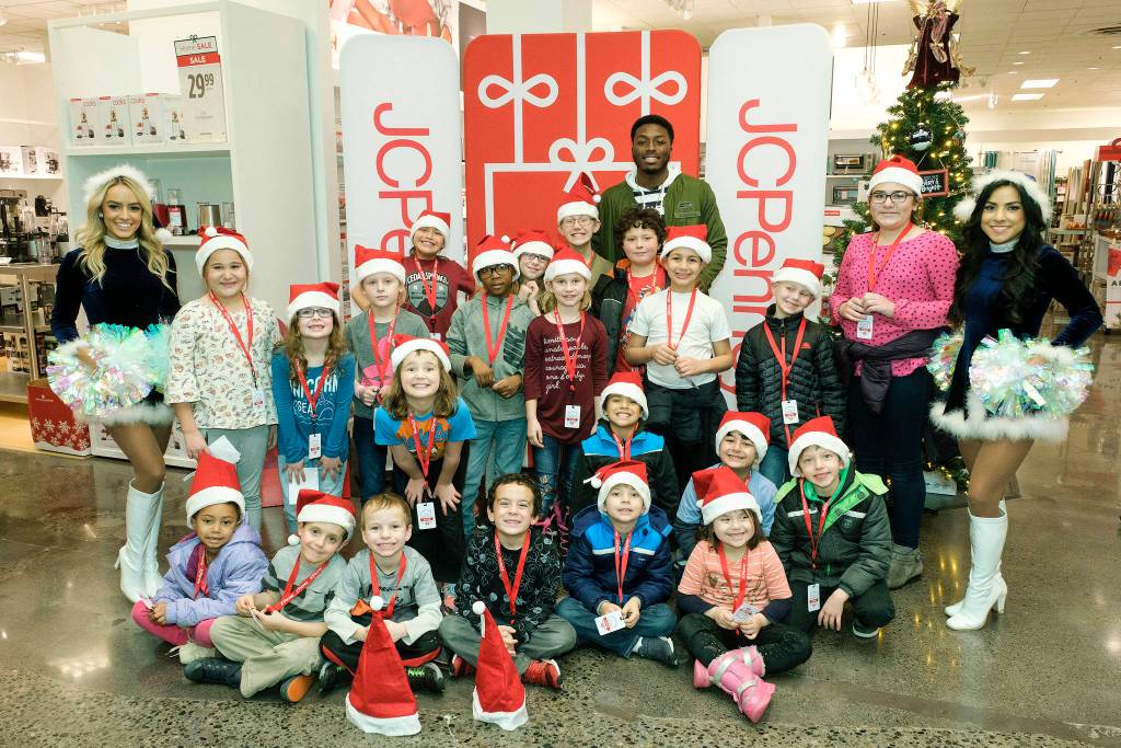 The Seahawks David Moore and SeaGals cheerleader Jessica, far left, and Shayne, far right, pose with kids from the Auburn Valley YMCA after-school program during the JCPenney Giving Spree on Tuesday, Dec. 11 in Tukwila. Stephen Brashear/AP Images for JCPenney