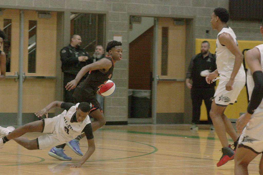 Roman Lewis (Graham-Kapowsin) of the 4A East team takes the ball up court as West defender DaeKwon Watson (Auburn) tumbles to the floor during the Sterling Athletics South Sound All-Star Game last Friday night. MARK KLAAS, Auburn Reporter