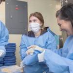 Lana Marshall, an Auburn Mountainview High School student, middle, laughs with the instructor while trying to gown up in the emergency room unit during MultiCares Annual Nurse Camp at Tacoma General Hospital. COURTESY PHOTO, Patrick Hagerty