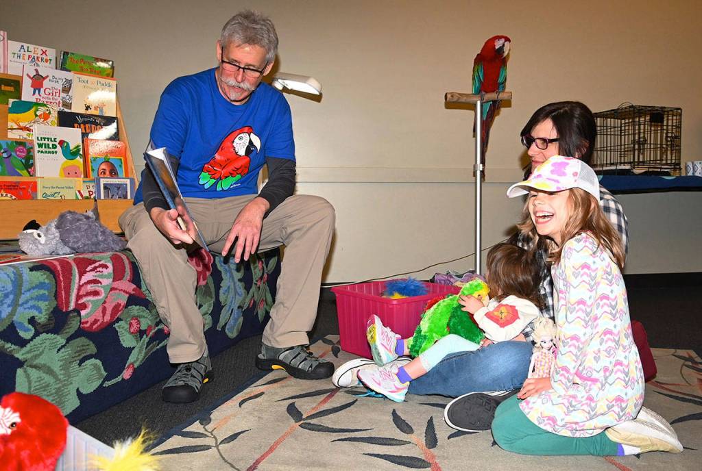Russ Campbell tells a parrot story to Esmeralda Salamone and her daughters Amalia, 7, and Artaea, 2, with the parrot Molly watching. RACHEL CIAMPI, Auburn Reporter