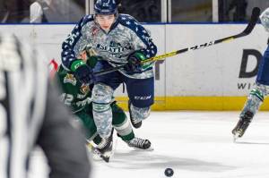 The Thunderbirds Owen Williams pushes the puck up the ice as the Silvertips Cole Fonstad tumbles during WHL play Saturday. COURTESY PHOTO, Brian Liesse, T-Birds
