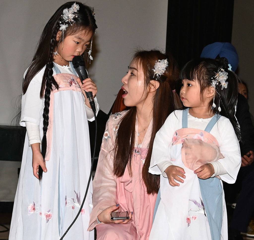 Liuxin Chen and her daughters Yolanda Liang, 6, and Janaya Liang, 3, sing on stage. Yolanda is singing with the mic. RACHEL CIAMPI, Auburn Reporter