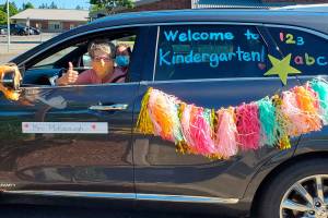 A Lakeland Hills Elementary teacher riding in the districts car and bus parade last week signals her eagerness to welcome students to school on opening day Sept. 9. Courtesy photo