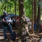 Homelessness Outreach Program Coordinator Kent Hay delivers mail to a resident of a camp on Aug. 27, 2021. Photo by Henry Stewart-Wood/Sound Publishing