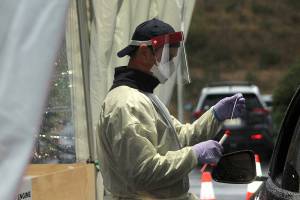 A South King Fire & Rescue firefighter places a used test swab into a secure COVID test vial on Nov. 18, 2020, at a Federal Way testing site. Olivia Sullivan/Sound Publishing