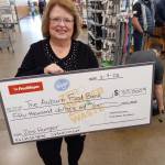 Auburn Food Bank director Debbie Christian is all smiles as she holds a replica of the $50,000 check given to the Auburn Food Bank by the Auburn Fred Meyer store. It was the stores entire bonus from the Washington State Lottery for selling the winning ticket in the recent Powerball jackpot. Photo by Robert Whale, Auburn Reporter.