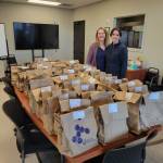 Tana Grames and Lindsay Relf stand with 203 meals-in-a-bag collected and assembled by the Auburn congregation of The Church of Jesus Christ of Latter-day Saints to support local families experiencing housing insecurity. Grames led the organization of the food drive and assembly event for church members. Courtesy photo