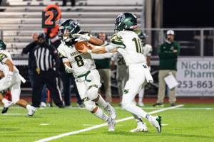 RJ Conlan #8 of the Auburn Trojans takes a handoff during a football game against the Sumner Spartans at Sunset Chev Stadium on Nov. in Sumner. Photos by Henry Rodenburg