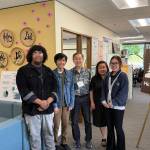 Executive Director Minh-Duc Nguyen (center right) and Ron Choi (center) rely on the work of volunteers to keep Helping Link running. Photo by Drew Dotson/Sound Publishing