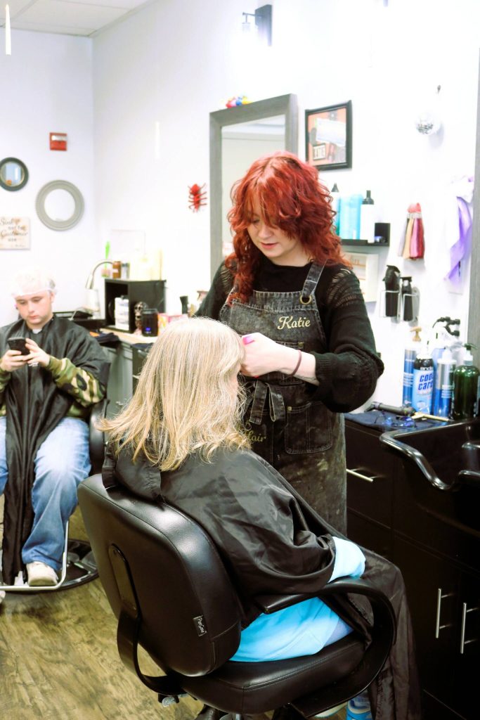 While waiting for one regular clients color to develop, Third Dimension Salon Auburn hairstylist Katie Francis trims his mothers bangs.