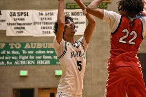 Isaiah Englund holds the ball over his head against the Redhawks at Auburn High School. Ben Ray / The Reporter