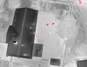 Drone thermal footage depicting the suspect sitting on the edge of the roof. Screenshot of Auburn police video.
