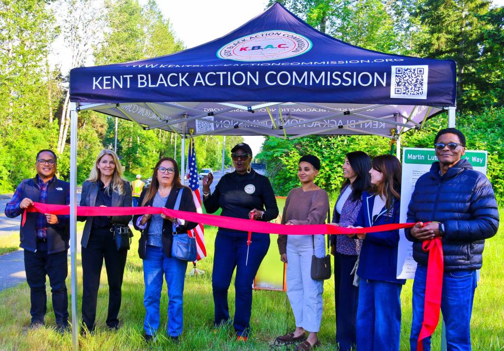 Several elected officials join Gwen Allen-Carston to welcome the new highway sign. From left to right: State Rep. Edwin Obras, state Sens. Tina Orwall and Claudia Kauffman, Kent City Councilmember Sharn Shoker, King County Councilmember Steffanie Fain, Kent City Councilmember Zandria Michaud and Kent City Councilmember John Boyd.